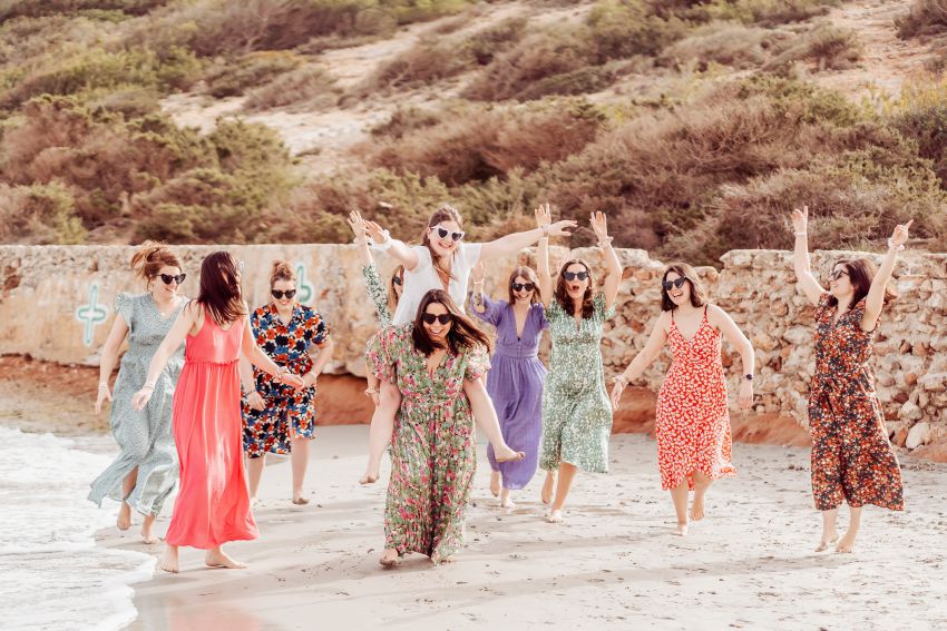 groupe evjf sur la plage en robes fleuries qui courent