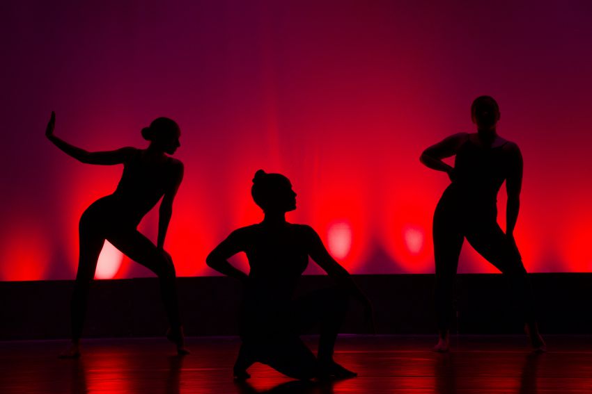 trois ombres de femmes sur une scene avec lumiere rouge